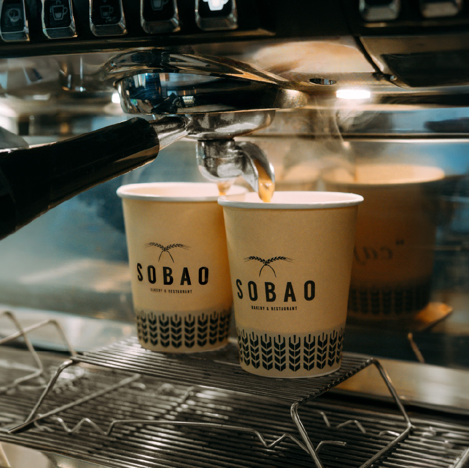 a photo of two sobao coffee cups being filled in a machine